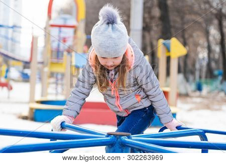 Happy child playing on rotating wheel toy at local playground at leisure time