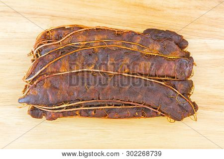 Top view of fresh sour Tamarind with brown shell removed to make Asian sour soup, on wooden background (Tamarindus indica) 