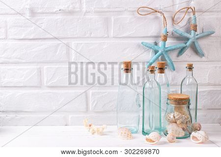 Nautical Or Marime Decorations Near By White Brick Wall. Decorative Blue Starfishes, Blue Bottles Wi