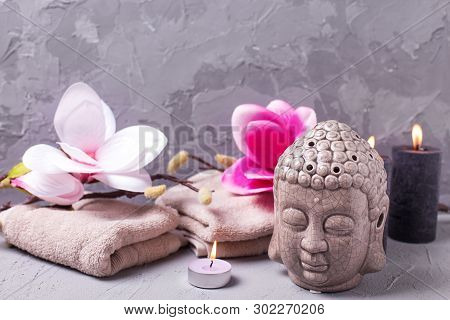 Black Burning Candles , Towels,  Decorative Buddha And Pink Magnolia Flowers On Grey Textured Backgr