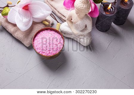 Sea Salt, Burning Candles, Buddha And Pink Magnolia Flowers On Grey Textured Background. Spa Concept