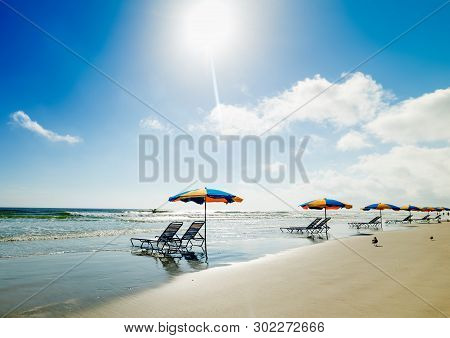 Beach Chairs And Parasols In Daytona Beach Under A Shining Sun. Florida, Usa