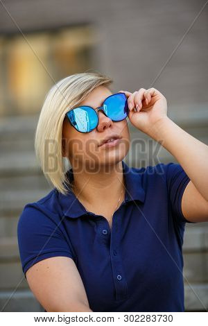 Stylish Girl Plus Size, Fashionable Haircut In Mirror Glasses Is Sitting On The Steps And Looking At