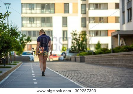 Sporty Stylish Girl Plussize In Sunglasses Goes Down The Path Past The Trees, Carries A Longboard An