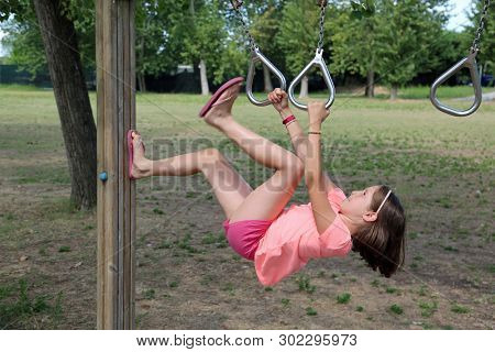 Little Girl Does A Gymnastic Exercise With Rings In A Health Path