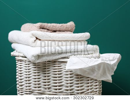Wicker Laundry Basket With Dirty Clothes And Clean Towels On Color Background