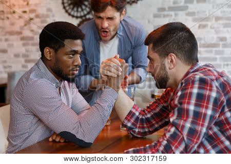 Challenge. Diverse Friends Arm Wrestling And Drinking Beer At Bar Or Pub