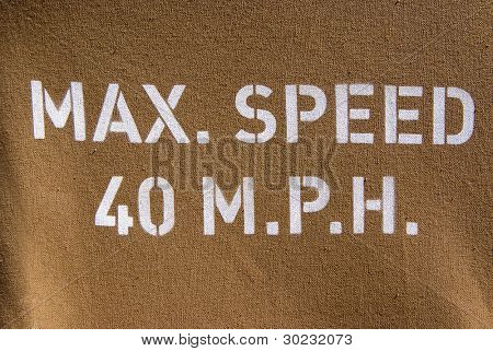 Warning sign of max speed 40 m.p.h. painted on an army jeep canvas