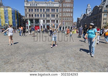 Amsterdam, Netherlands - July 02, 2018: Children Catch Soap Bubbles In The Central Dam Square In Ams