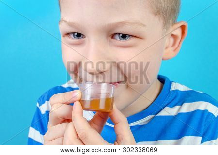 Boy Takes Multi Vitamin Syrup On Blue Background