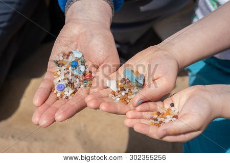 Family Of Mother And Children Holding And Showing Small Tiny Harmful Plastic Beads Collected On The 