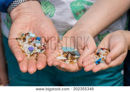 Family Of Mother And Children Holding And Showing Small Tiny Harmful Plastic Beads Collected On The 
