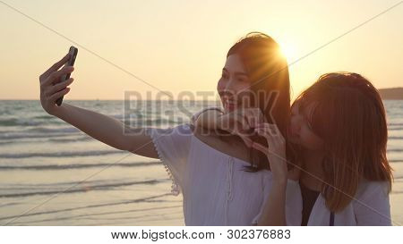 Young Asian Lesbian Couple Using Smartphone Taking Selfie Near Beach. Beautiful Women Lgbt Couple Ha