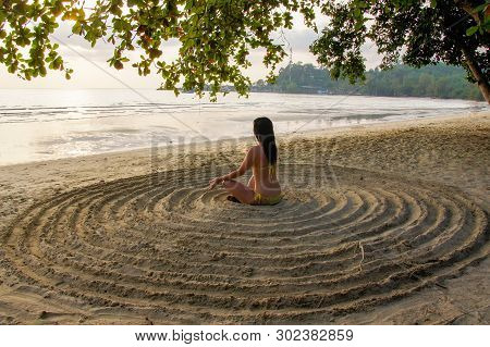 The Girl Sits Back On The Sandy Beach In The Center Of An Impromptu Circle And Meditates