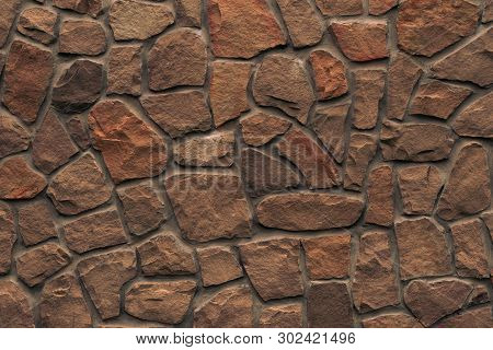 Orange Stone Wall. Bright Brown Rock Texture. Red Faceted Stone Wall Background For Design. Modern A