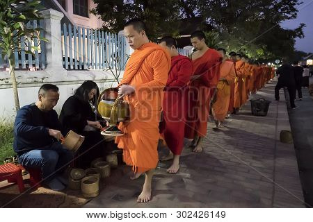 Luang Prabang - 15 January 2019: People Giving Alms To Buddhist Monks On The Street Luang Prabang, L
