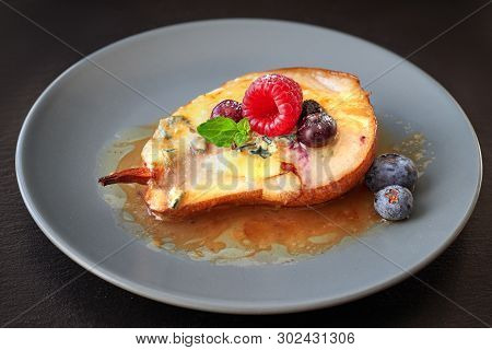 Closeup On Half Baked Pear With Blue Cheese And Sugar. The Pear Is Served With Raspberry, Blueberry 