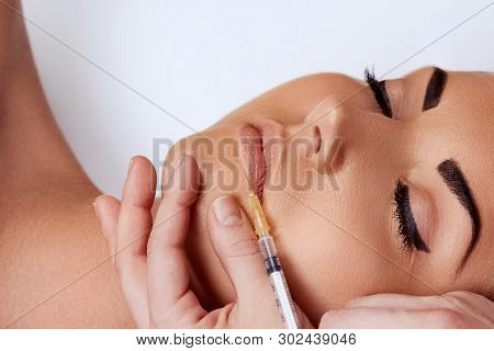 Closeup Of Beautiful Woman Getting Cosmetic Injection Of Botox In Lips. Girl In Beauty Salon. Proced