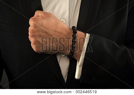 Male Fist With Bracelet On Formal Suit Background. Bracelet Or Amulet On Wrist. Amulet Concept. Hand