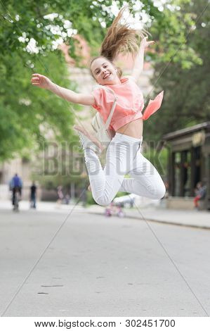 Bouncy And Energetic. Energetic Little Child In Motion On City Street. Lively Small Girl Jumping Wit
