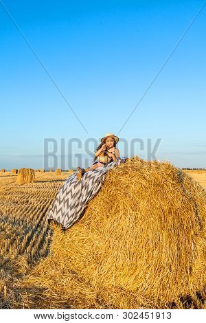 Cute Little Child In Rye Field With Hay Stacks On Sunset.