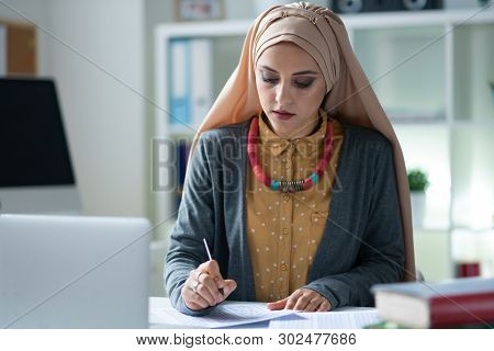 Stylish Muslim Teacher Wearing Hijab Feeling Busy Correcting Tests