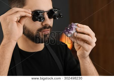 Male Jeweler Evaluating Semi Precious Gemstone In Workshop, Closeup