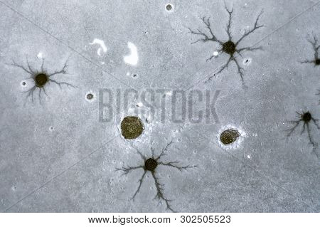 An Aeiral Drone Looking Down Captures Holes And Cracks In Frozen Lake Ice. Dark And Dusty Water Bene
