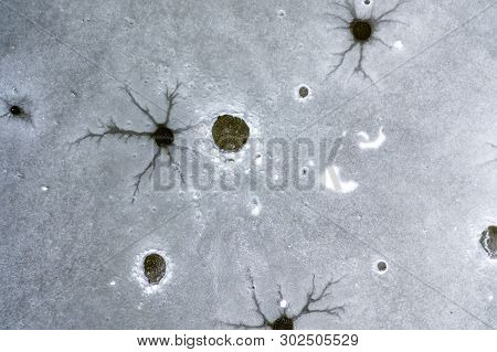 An Aeiral Drone Looking Down Captures Holes And Cracks In Frozen Lake Ice. Dark And Dusty Water Bene
