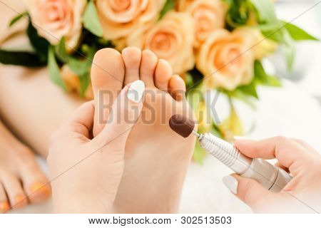 Podiatrist in podiatry session working of feet of client with machine