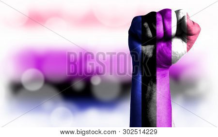 Flag Of Genderfluid Painted On Male Fist, Strength, Power, Concept Of Conflict. On A Blurred Backgro