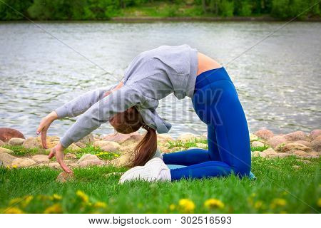 Young Girl Goes In For Sports In Nature. Healthy Lifestyle.flaxible Child Doing Joga Poses Bridge St