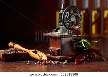 Vintage Pepper Mill With Various Peppers And Spices. Old Pepper Mill With Cooking Utensils, Bottles 