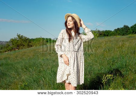 Half Length Portrait Of A Charming Positive Woman Dressed In Long White Summer Dresses With A Straw 