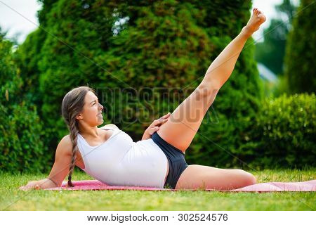 Expectant Woman Doing Side Reclining Leg Lift In Park