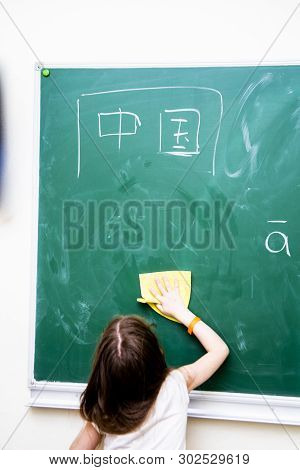 Girl Wipes A Green School Board From Chinese Characters