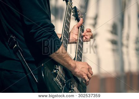 A Street Musician Performs A Solo On An Electric Double-necked Guitar