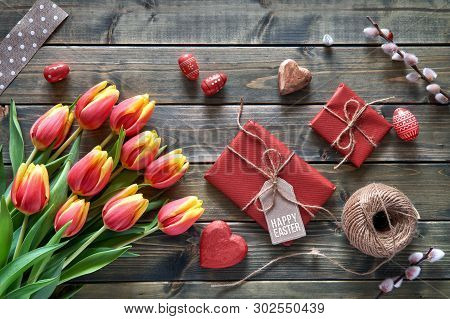 Easter Arrangement: Red Tulips, Wrapped Gifts, Cord And Decorative Hearts On Wooden Tabke, Flat Lay.