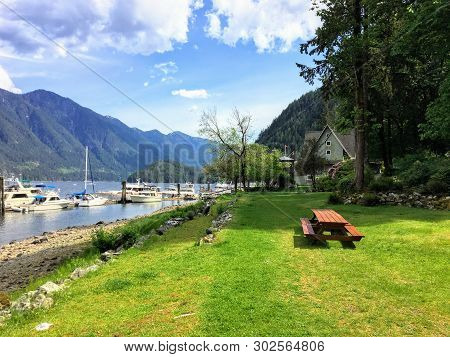 A Faraway View From The Shore Of A Beautiful Marina Full Of Boats And Old Inn, Surrounded By Forest 