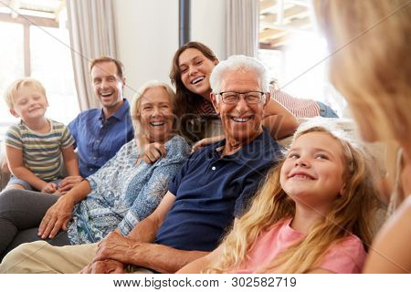 Multi-Generation Family Sitting On Sofa At Home Relaxing And Chatting

