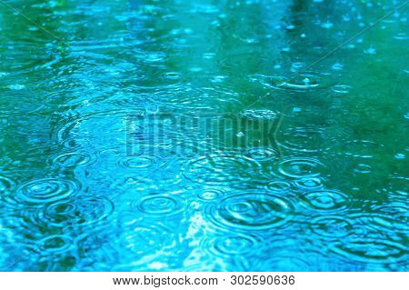 Raindrops On A Puddle On A Rainy Day. Blue Tone. Beautiful Background.