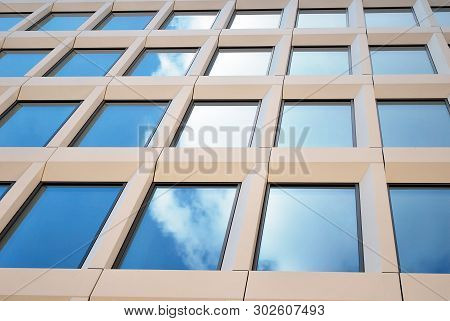 New Office Building In Business Center. Wall Made Of Steel And Glass With Blue Sky.