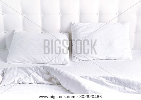 Soft White Quilted Pillow And Blanket Coverlet In Bed On The Background Of White Leather Quilted Hea