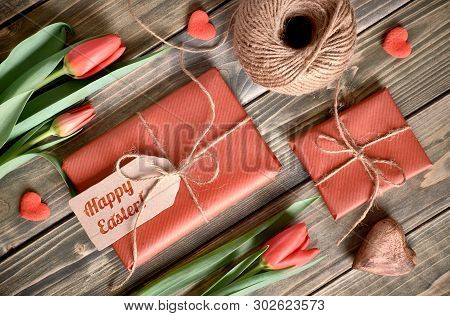 Easter Arrangement: Red Tulips, Wrapped Gifts, Cord And Decorative Hearts On Wooden Tabke, Flat Lay.