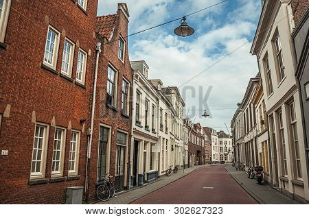 Empty Street With Semidetached Brick Houses And Bicycles In Front Of Doors At Sunset And Blue Cloudy