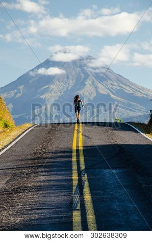 Running Girl In Green T-shirt On The Road With Mountain Taranaki In The Background With Clouds Above