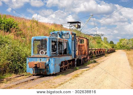 Old Rusty Locomotive With A Row Of Coal Vagons And  Bucket Chain Excavator Outdoors In Brandenburg, 