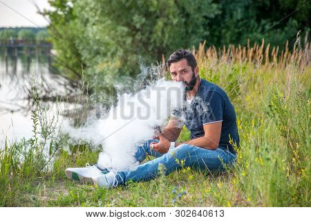 Stylish Brutal Man Using Vape To Vape Instead Of Smoking. Non-tobacco Smoking.