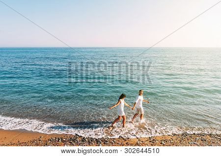 Couple In Love Having Fun On The Beach. Honeymoon Trip. The Couple Are Traveling. Man And Woman On T