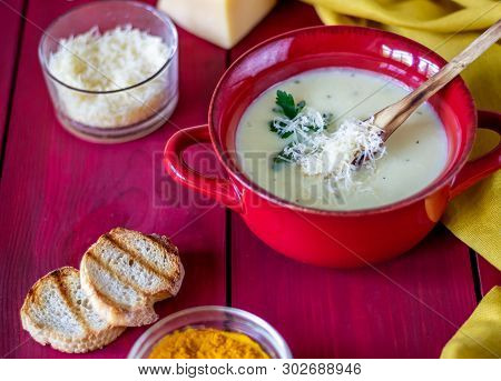 Cheese Cream Soup On A Red Wooden Background. White Bread Croutons. Ingredients.